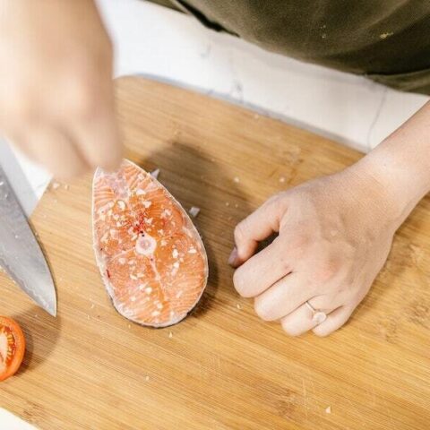 Salting a fish on a wooden cutting board.