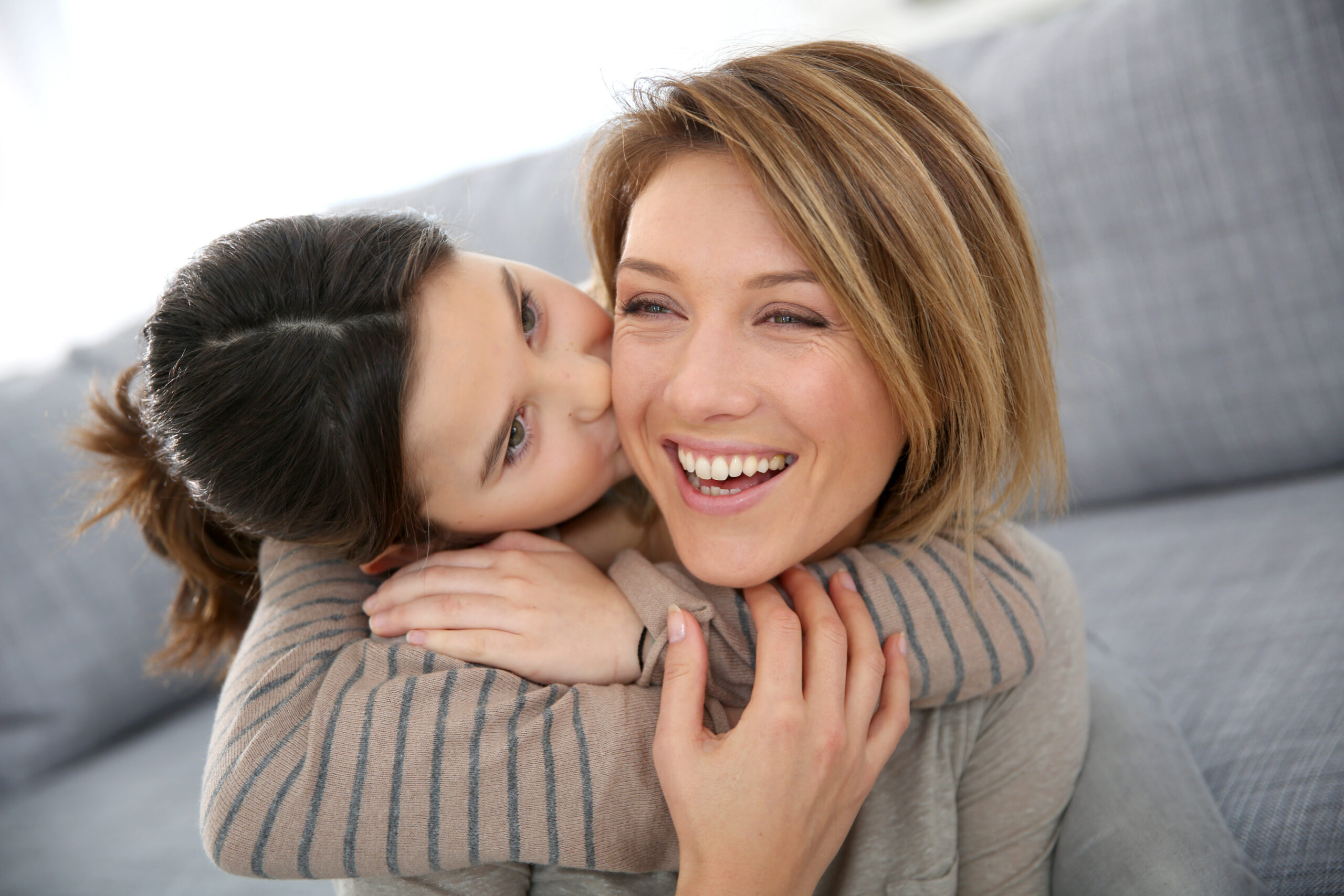 A girl hugs and kisses her mom