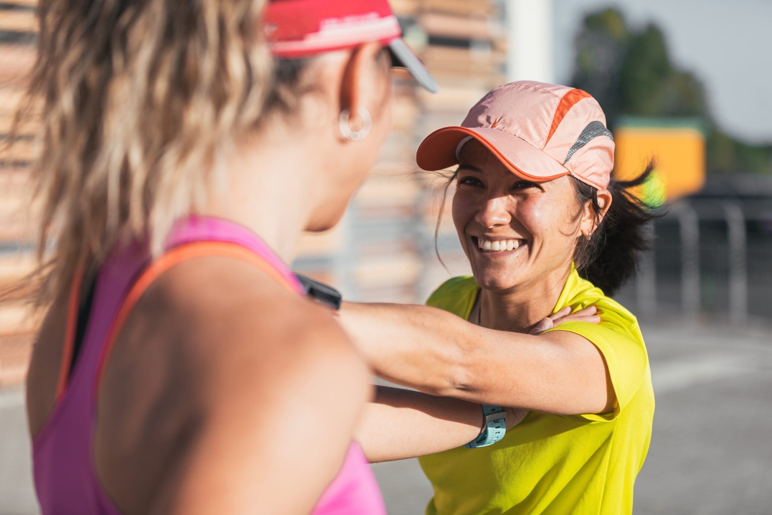 Two women prepare for a running workout by supporting each other as the stretch