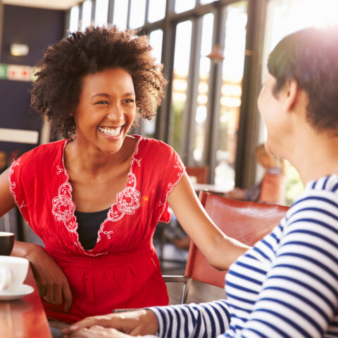 A vibrant, healthy woman talks with a friend over coffee