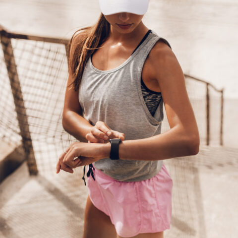 A fit 30 year old woman checks her sports watch after a run near a beach