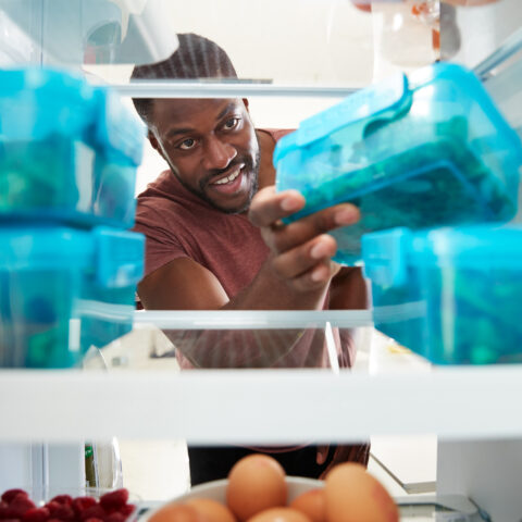 man reaching for one of his meal prepped containers in the refrigerator