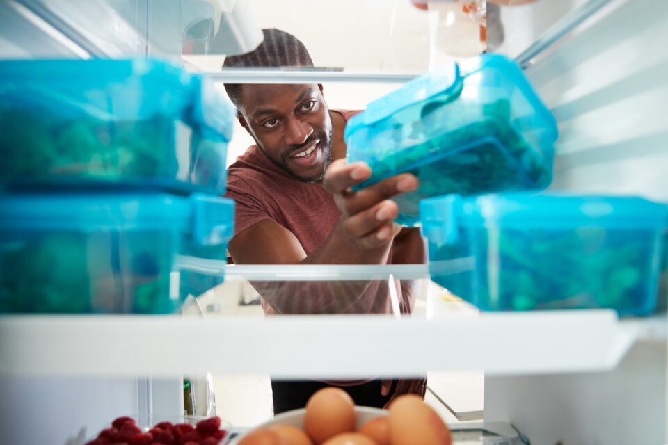 man reaching for one of his meal prepped containers in the refrigerator