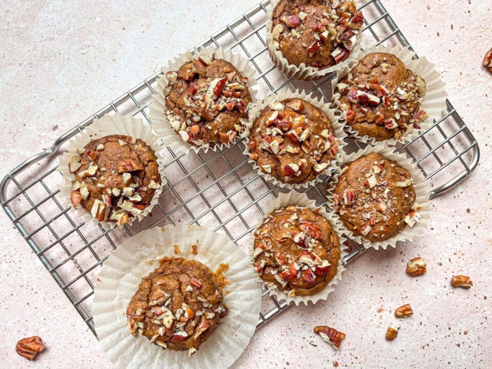 Pumpkin Spice Muffins cool on a cooling rack on a white counter with charismatic crumbs sprinkled with care