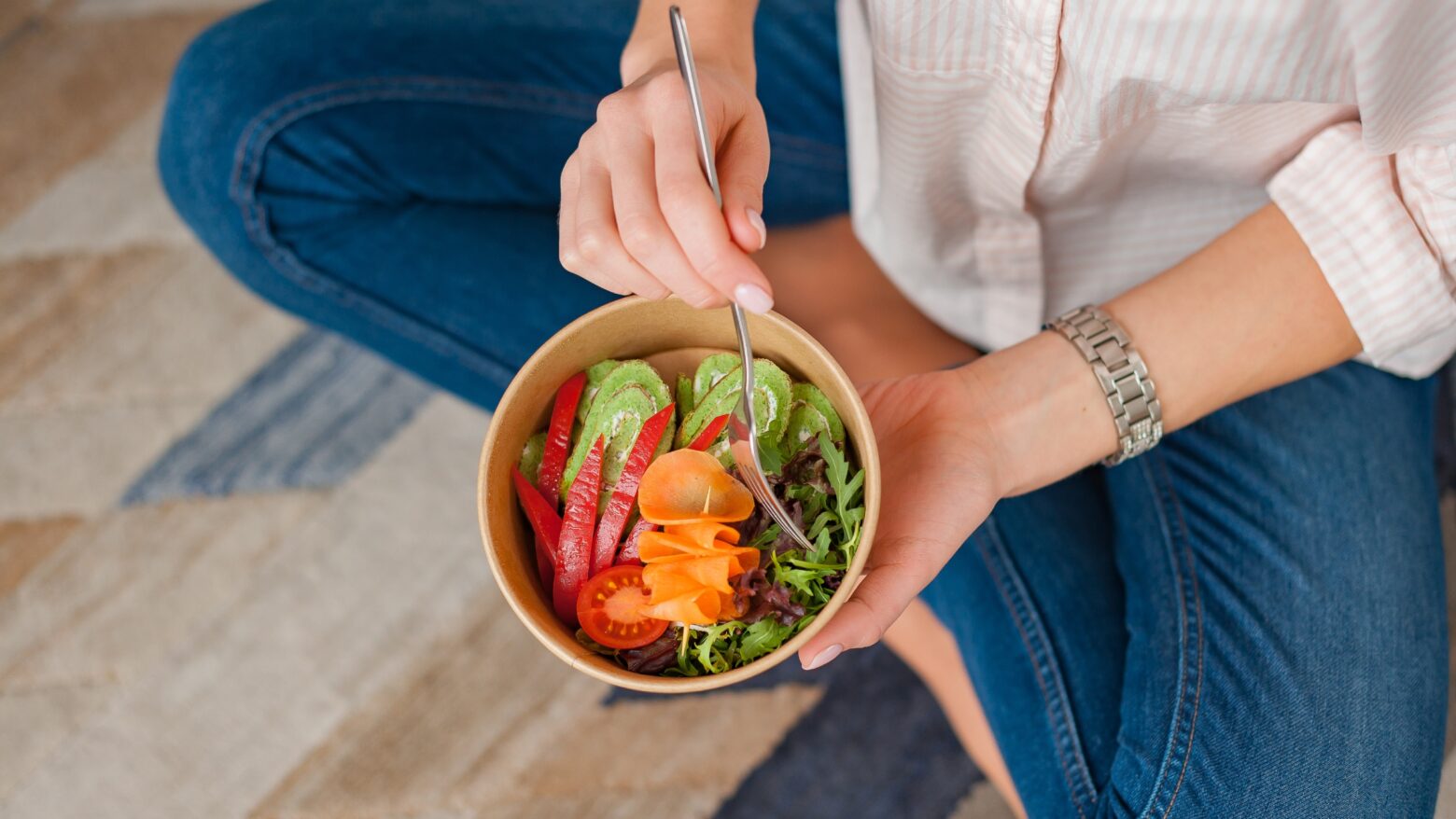 Woman eating a salad out of a paper bowl