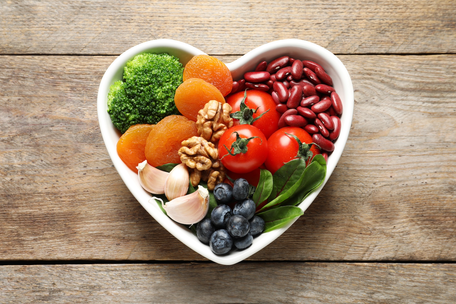 A heart-shaped bowl full of fruits and veggies