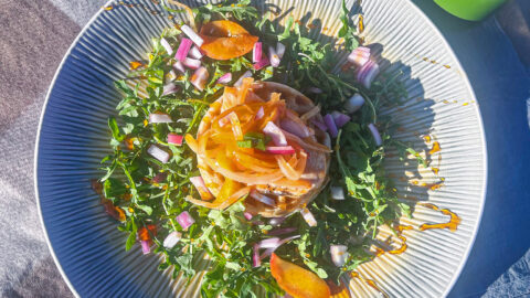 Open-face chicken & waffle sandwich on a bed of arugula