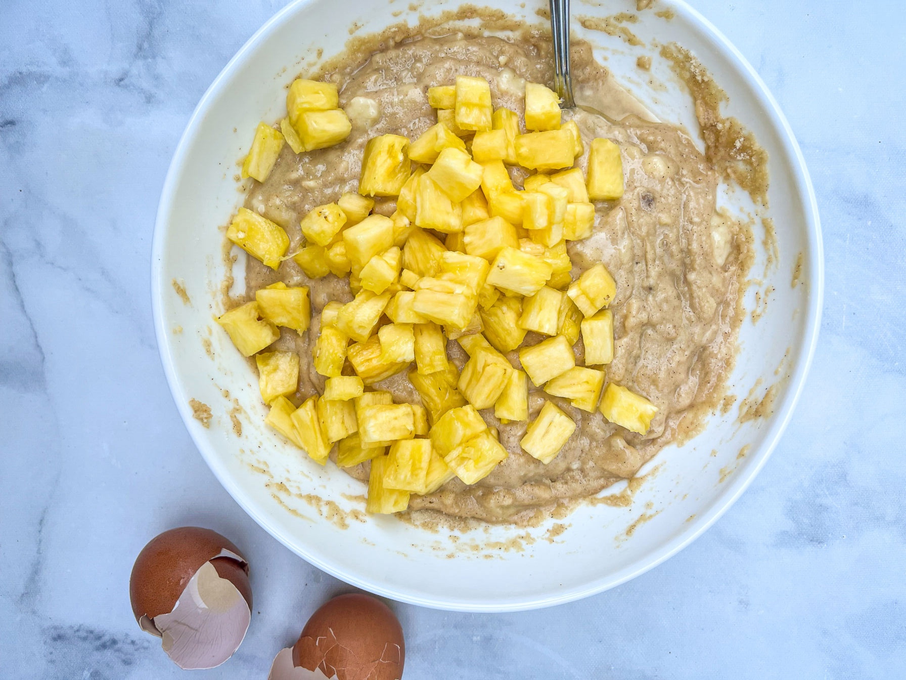 mixing pineapple coconut muffins batter in a bowl