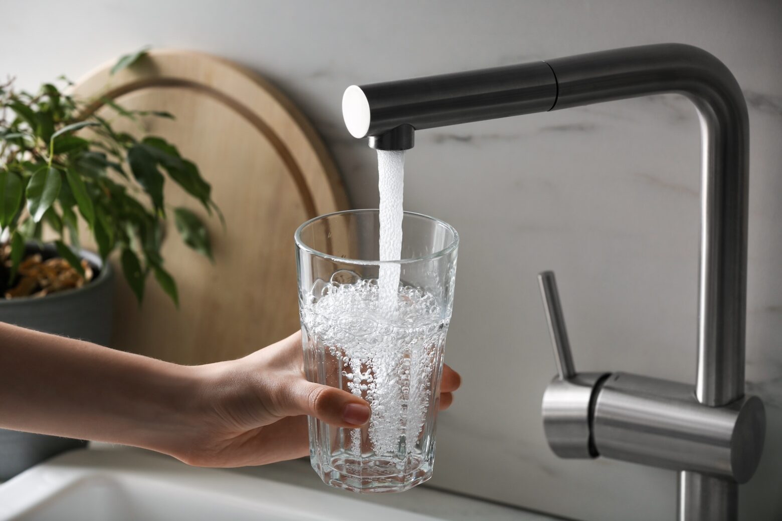 women turning on tap water and filling up the cup