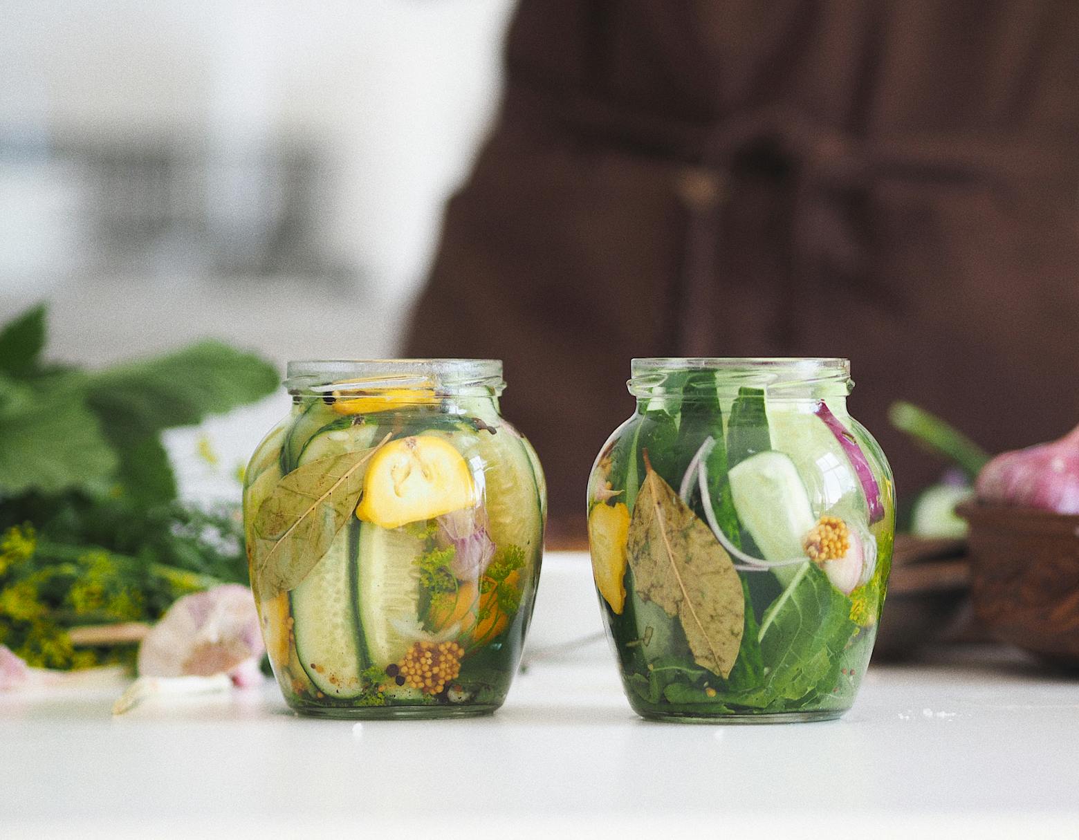 Clear Glass Jar With Green Leaves and Pickled Vegetables.