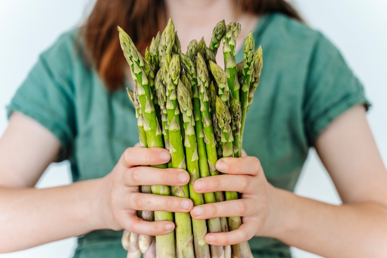 Stock photo of a woman holding a cluster of asparagus.