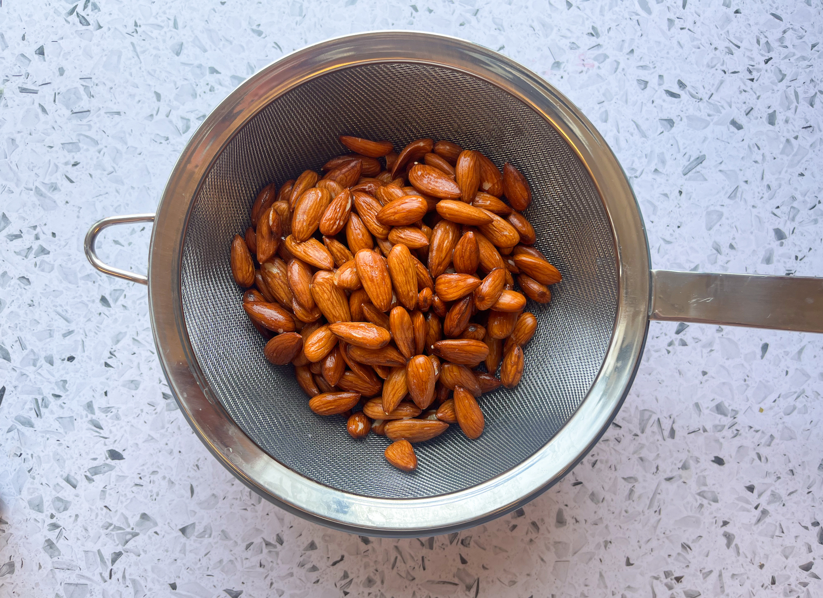 Soaked almonds being strained from above