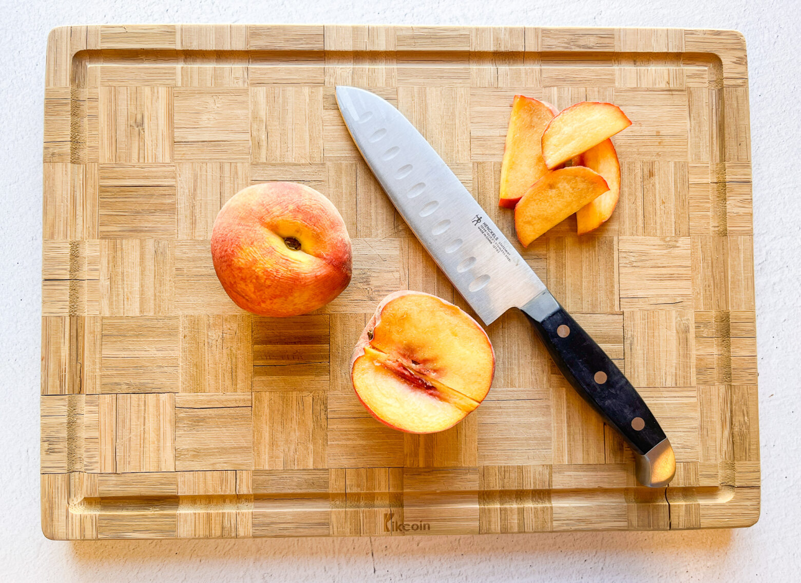 Iced peach green tea prep on a cutting board slicing peaches.