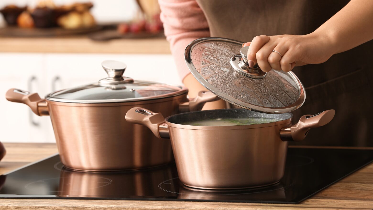 Close-up of a woman checking food cooking in pots on a stove