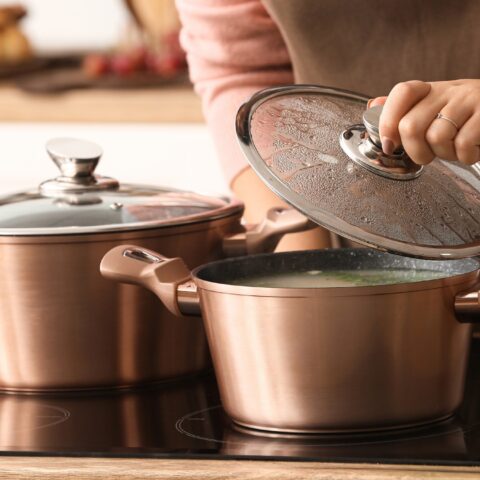 Close-up of a woman checking food cooking in pots on a stove