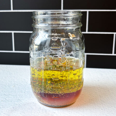 Photo of all oils and spice ingredients in a jar for Italian dressing.