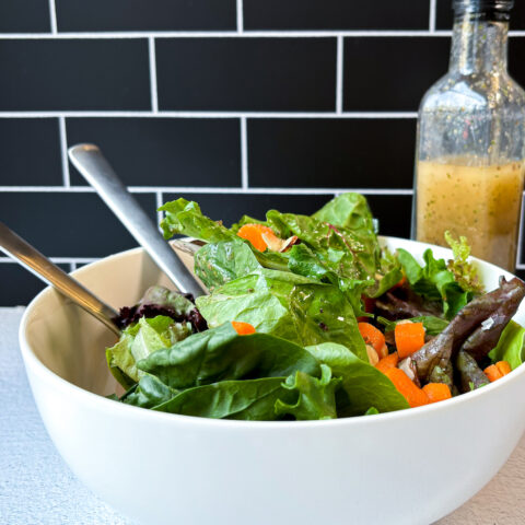 Final photo of Italian Dressing on salad with a bottle of the dressing in the background