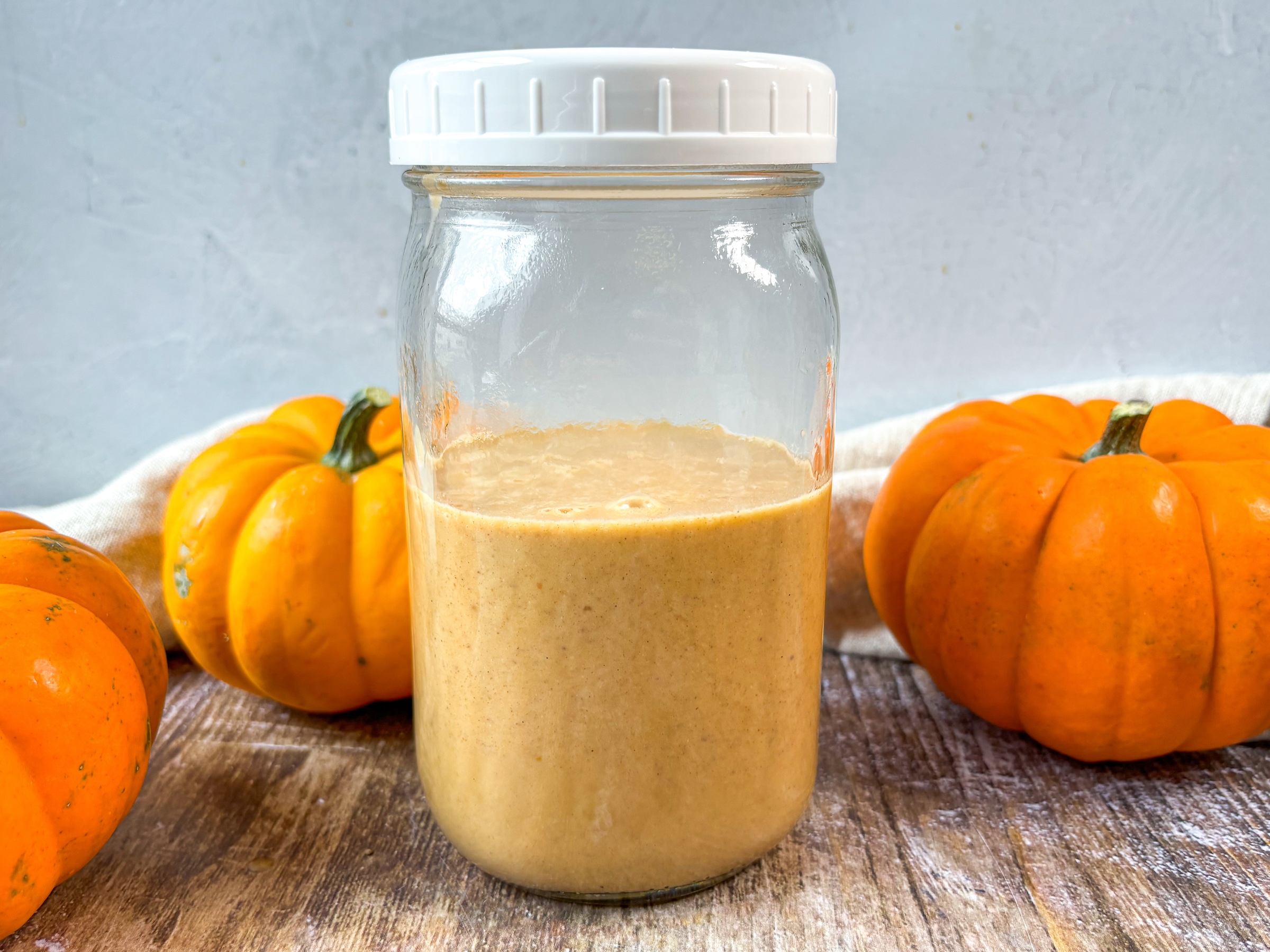 Pumpkin coffee creamer in a mason jar with pumpkins. 