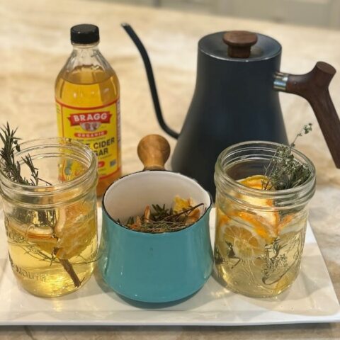 Herbal apple cider vinegar tonic with ingredients on a kitchen counter