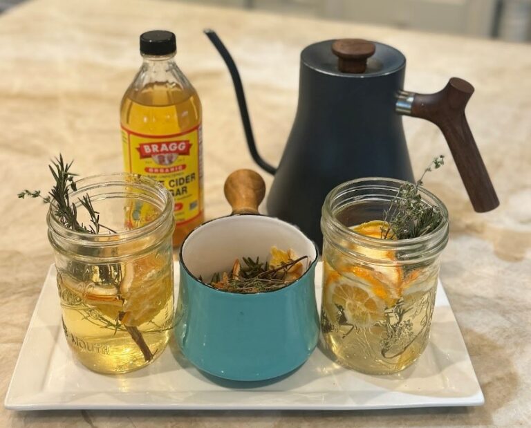 Herbal apple cider vinegar tonic with ingredients on a kitchen counter