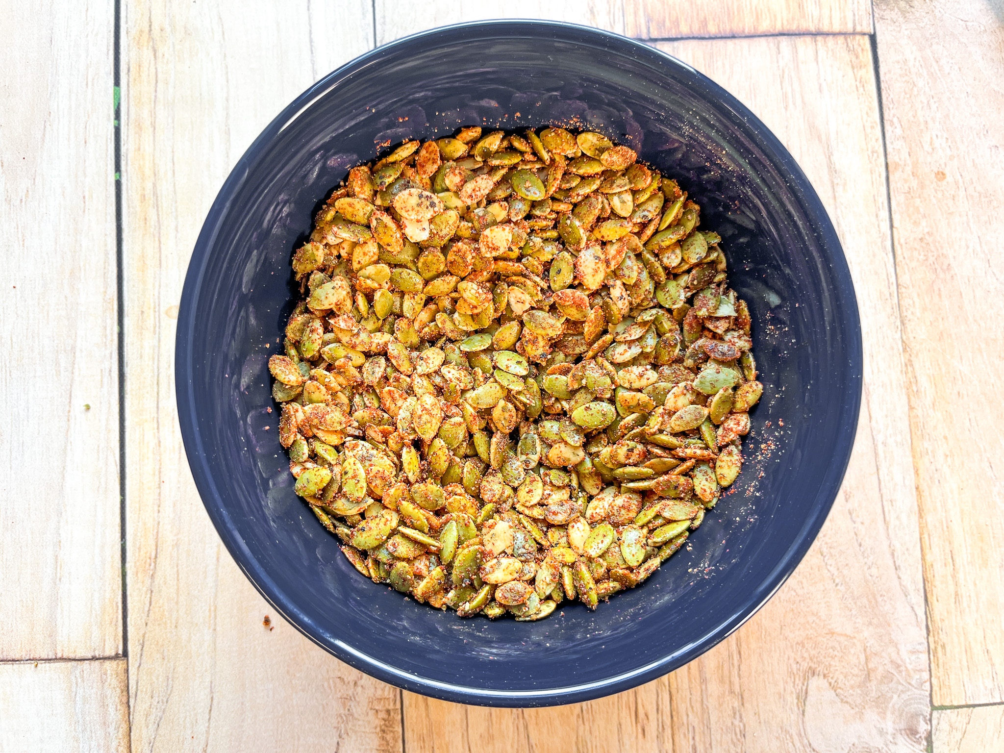 Spiced pumpkin seeds in a bowl before being cooked. 