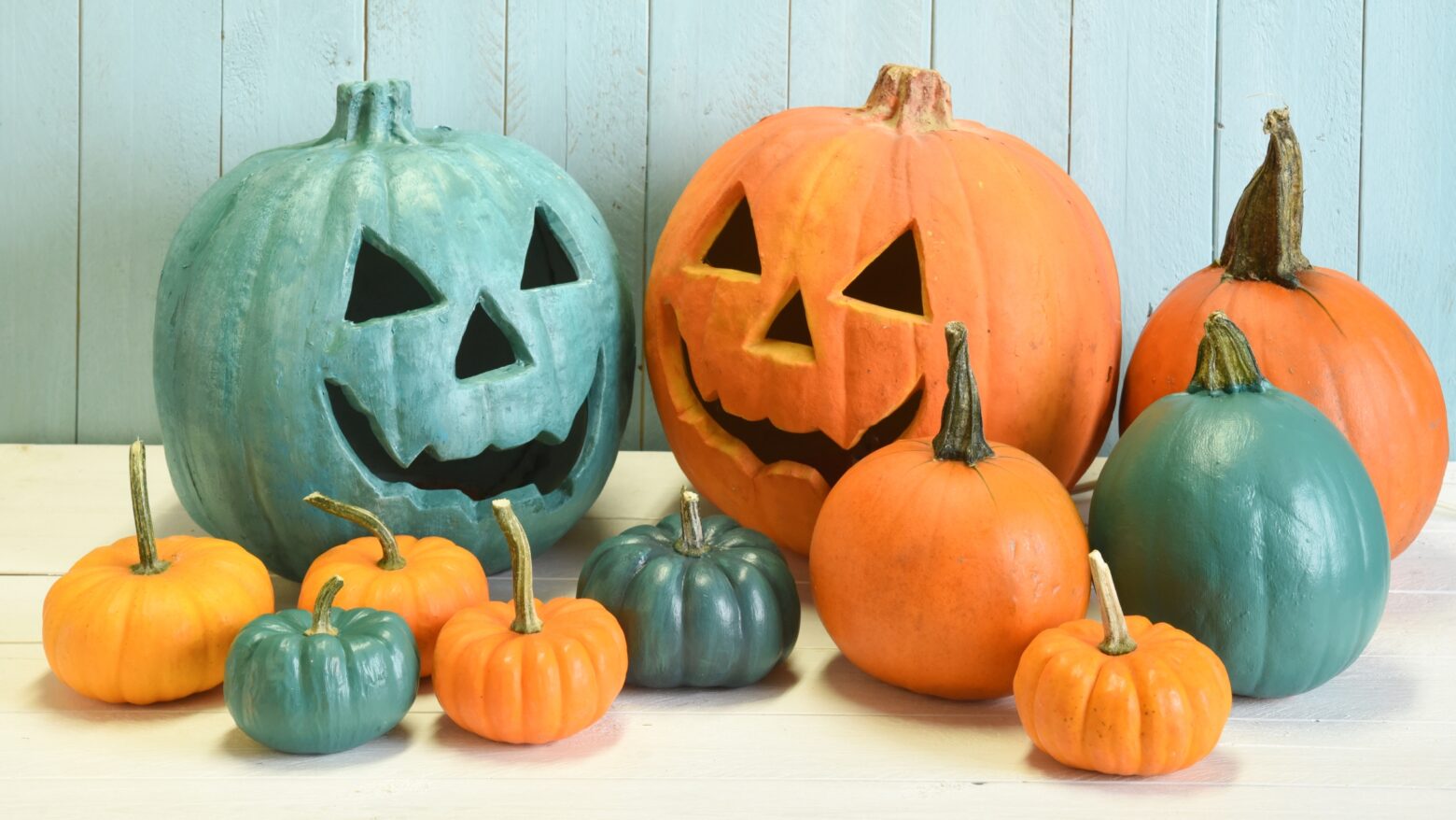 Teal pumpkins and jack-o-lanterns mixed with normal orange pumpkins and jack-o-lanterns