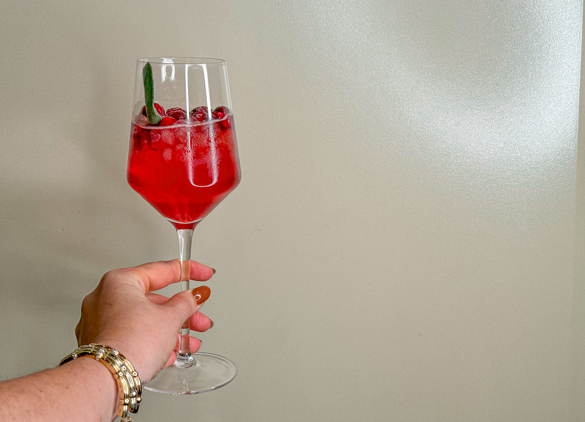 Cranberry Mocktail in a wine glass being held. 