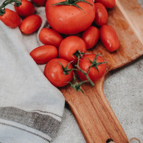 A collection of ripe tomatoes on a wooden chopping board, perfect for culinary presentations.