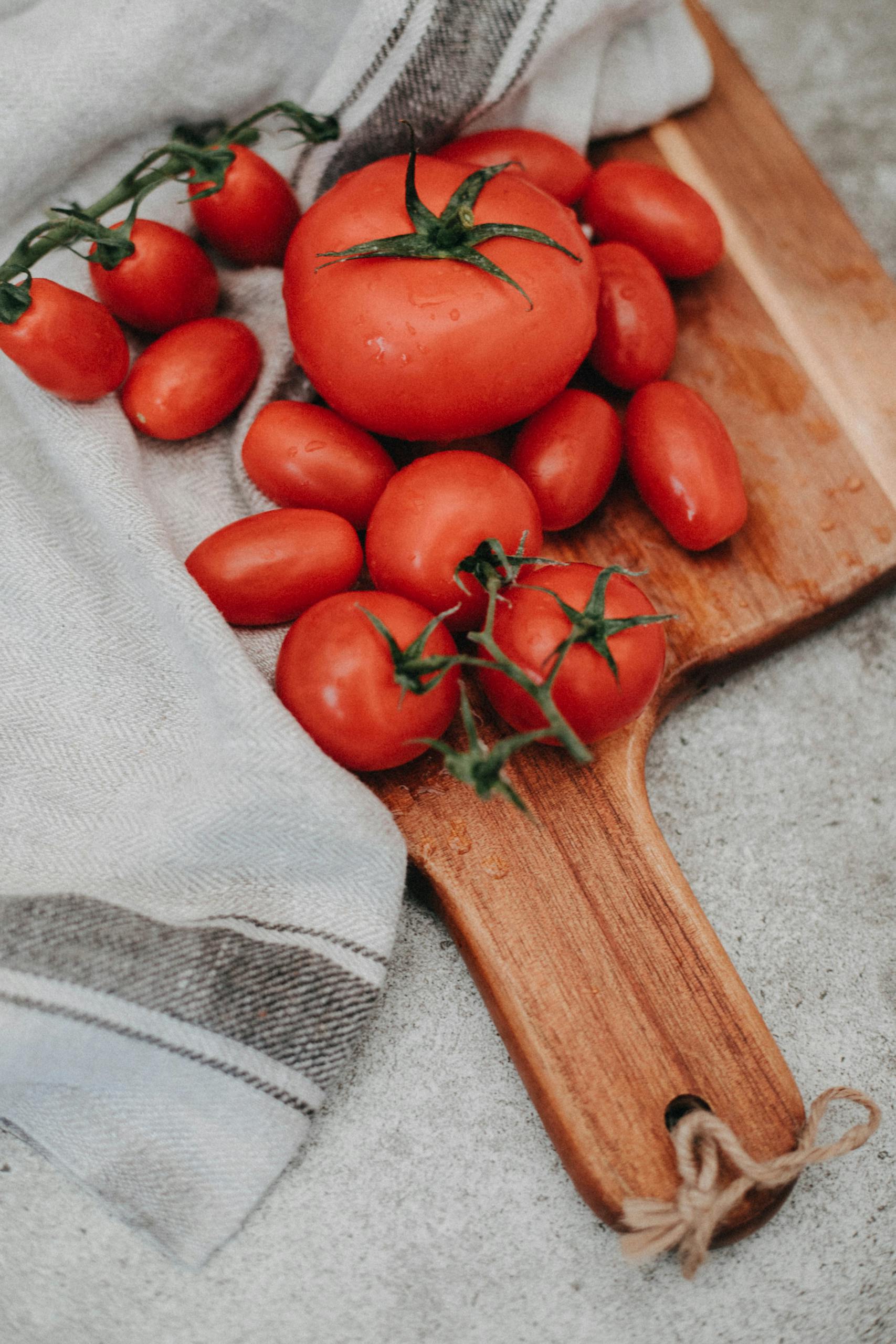 A collection of ripe tomatoes on a wooden chopping board, perfect for culinary presentations.