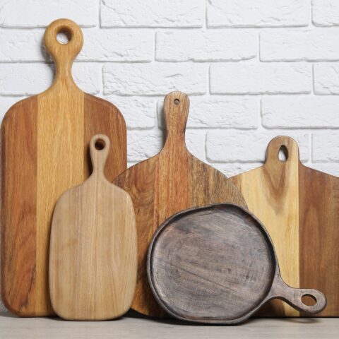 A variety of wooden cutting boards against a white brick wall