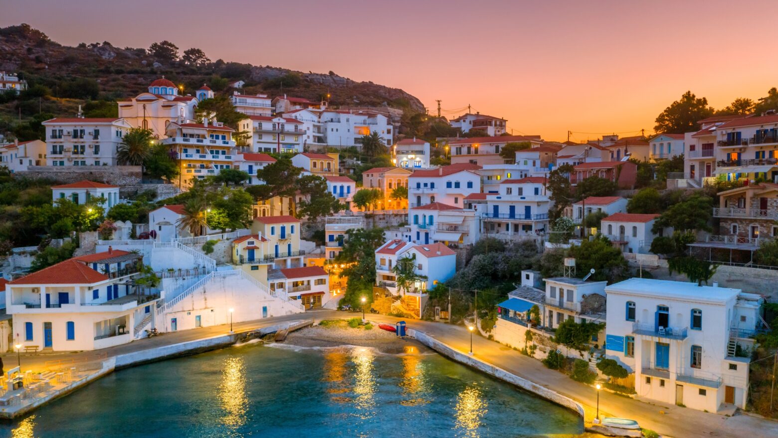 A cluster of white houses on a coastal hill at sunset