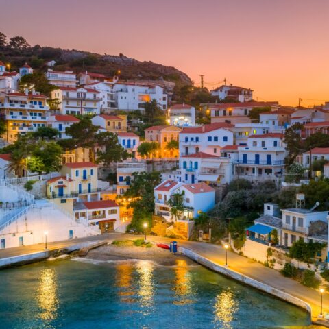 A cluster of white houses on a coastal hill at sunset