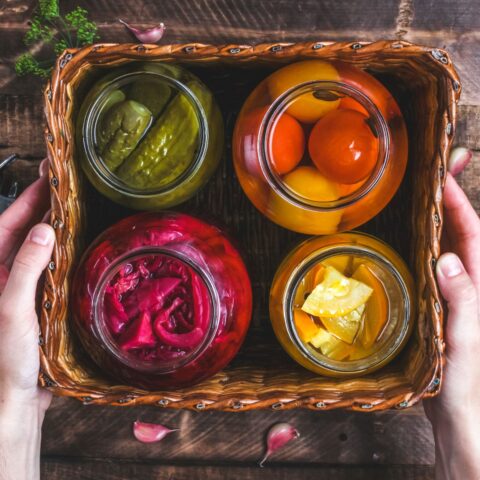 Above shot of 4 jars of pickled vegetables in a square basket