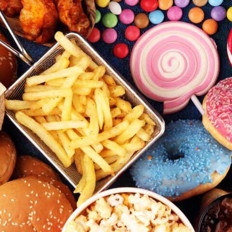 An array of ultra-processed foods including burgers, popcorn, fries, donuts, and candy