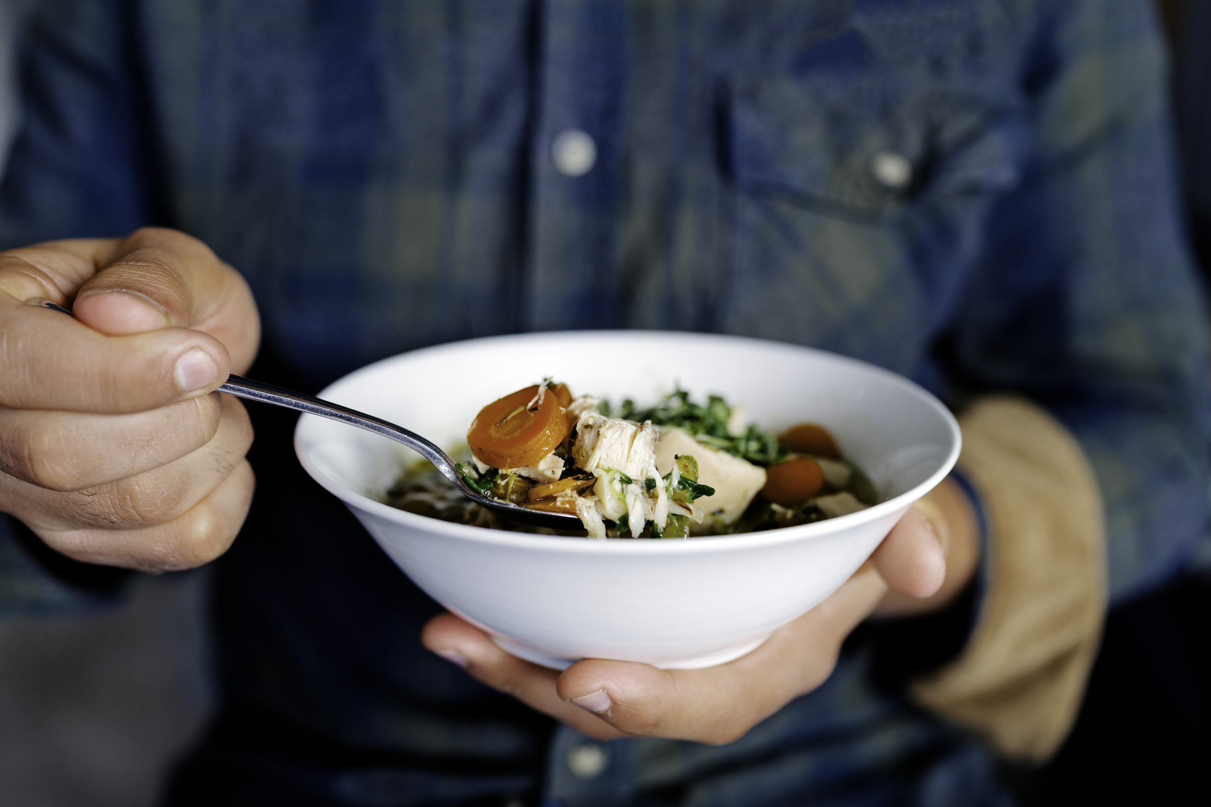 Someone enjoying a bowl of mustard chicken soup.