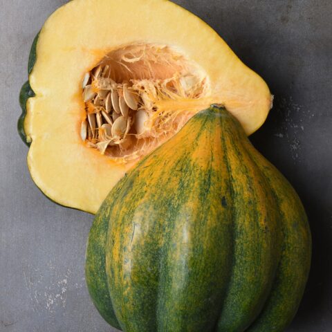 Acorn squash cut in half on a baking sheet.