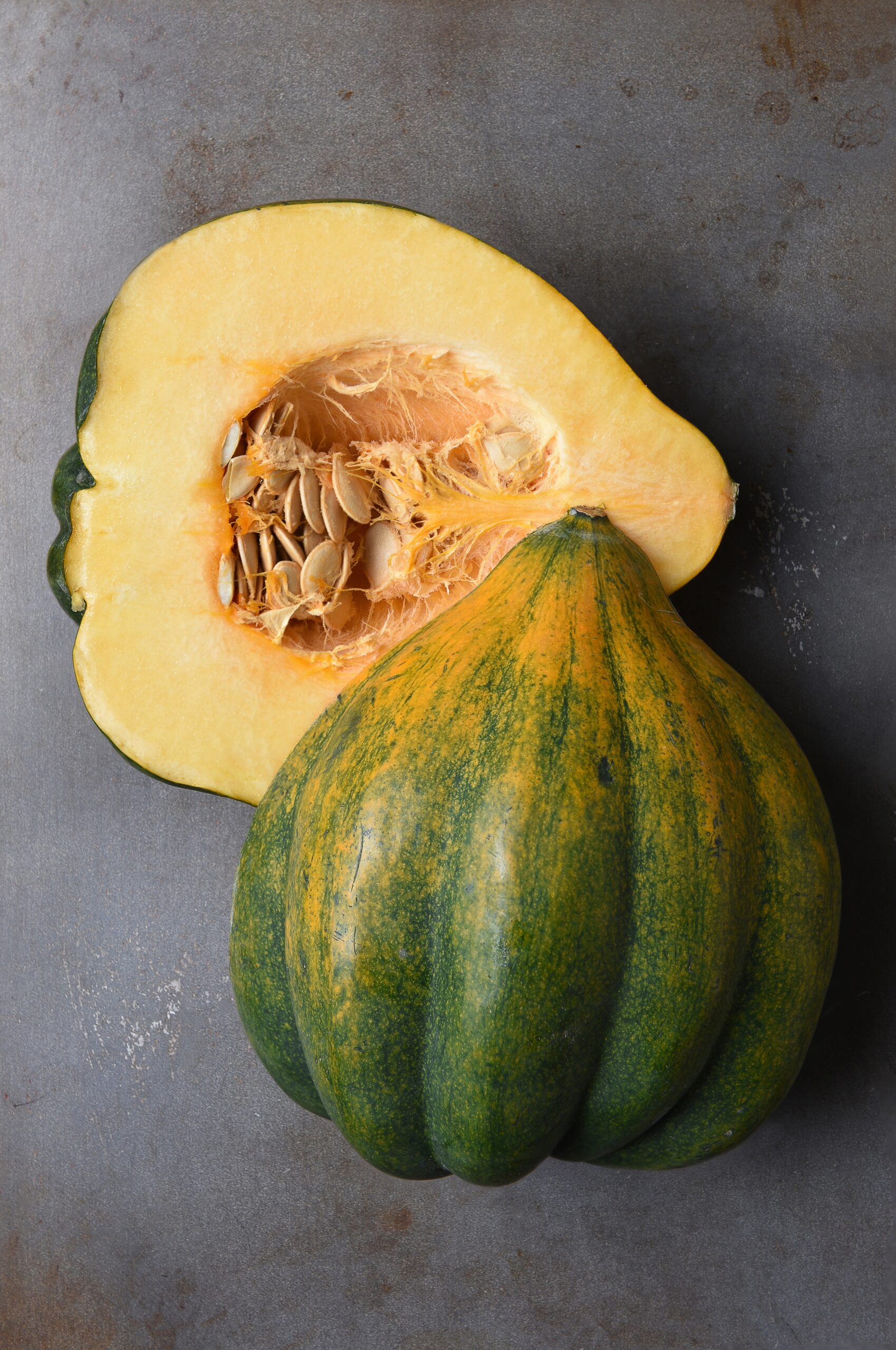 Acorn squash cut in half on a baking sheet.