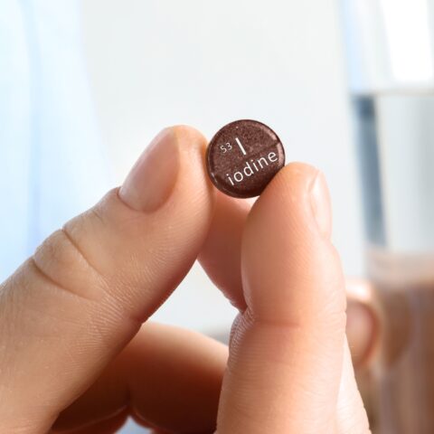 Closeup of a hand holding a small brown iodine tablet