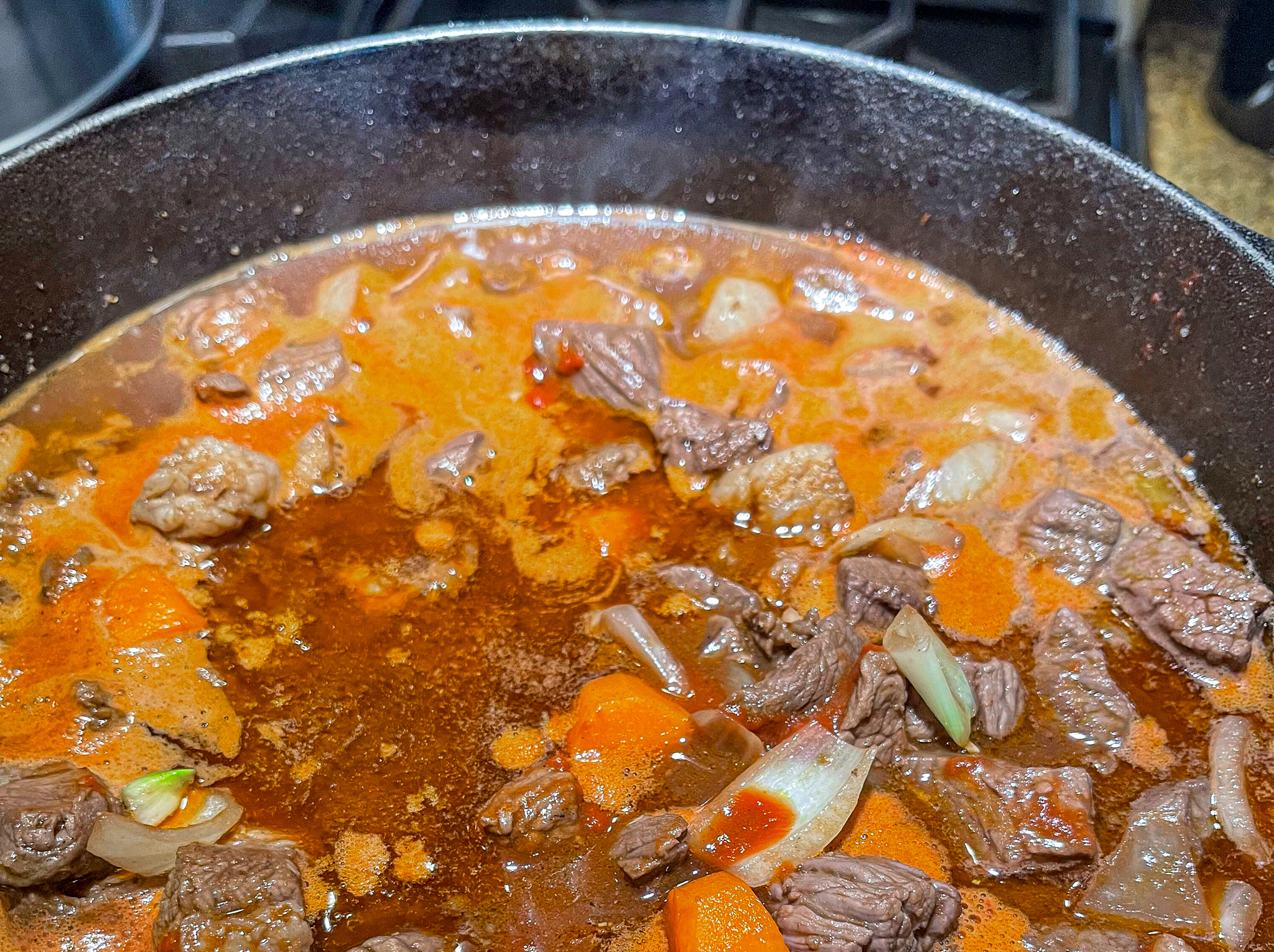 Beef bourguignon in a cast iron over the stove cooking.  