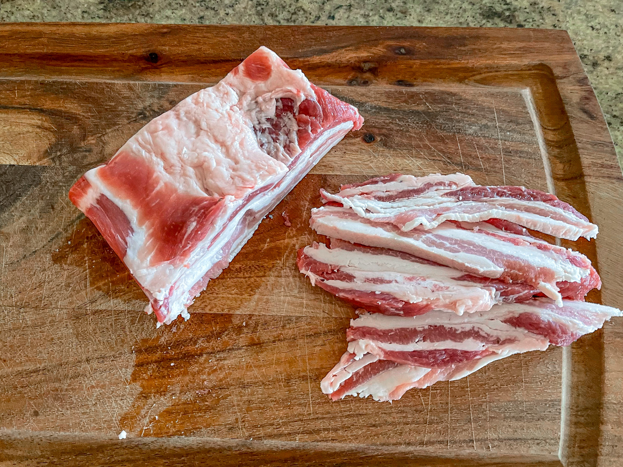 Making beef bourguignon by prepping the pork belly on a cutting board. 