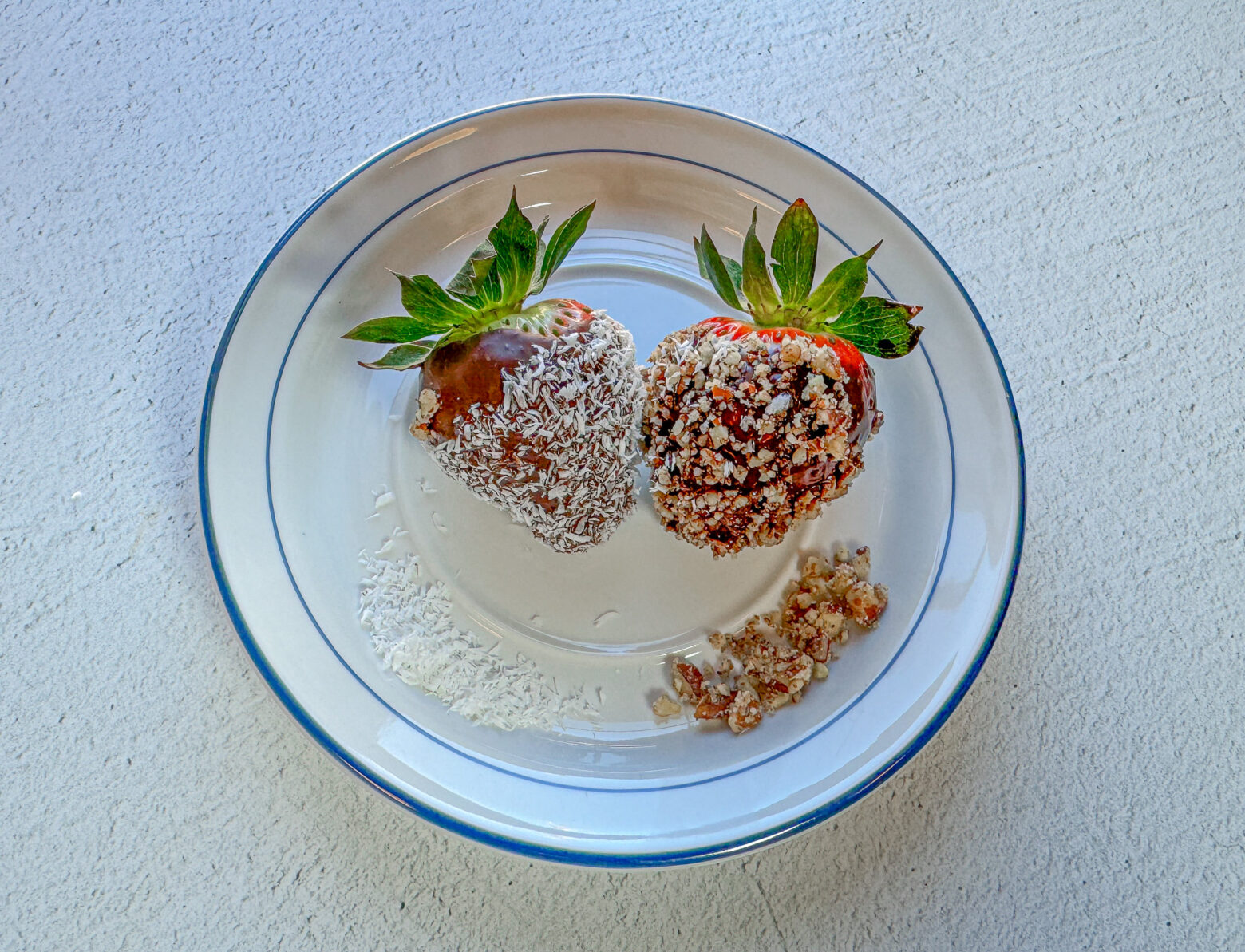 Pecan and coconut flavored chocolate-covered strawberries finished on a plate.