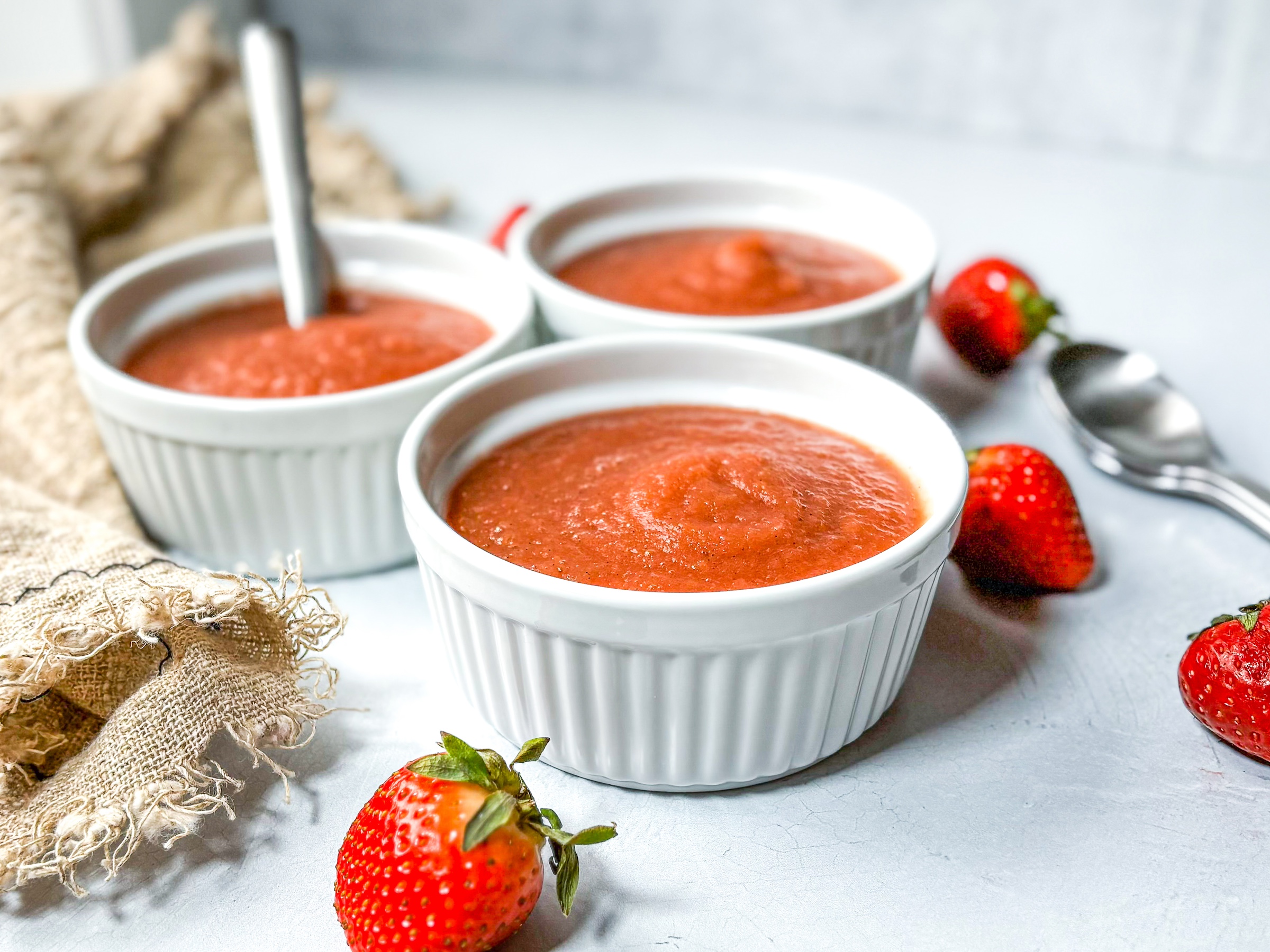 Strawberry applesauce in small dishes with whole strawberries. 