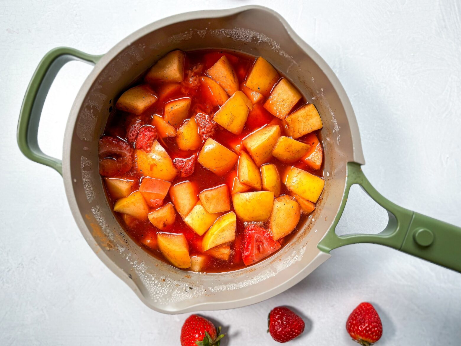Strawberry applesauce being made over the stove.