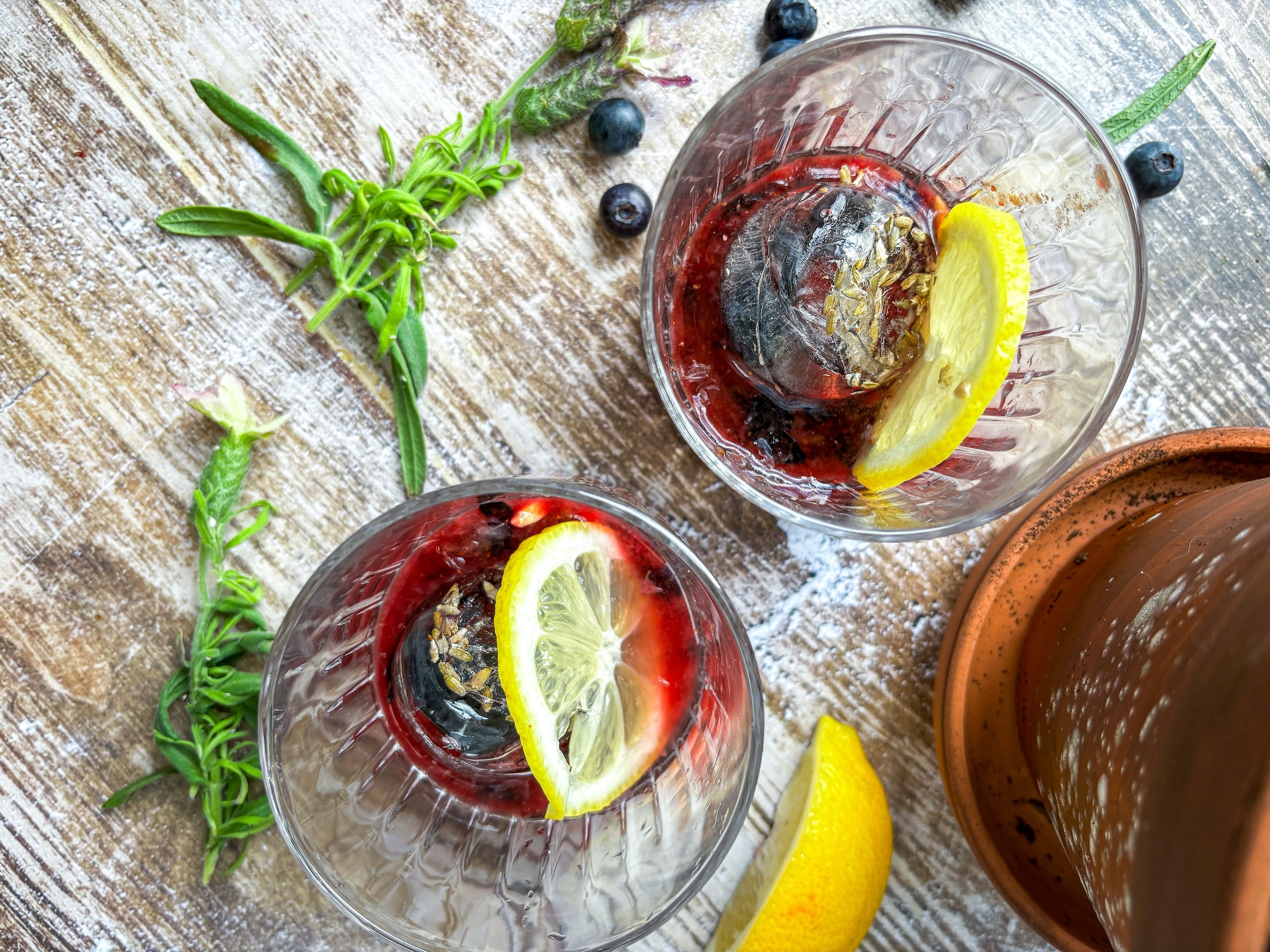 Blueberry-lavender mocktail finished from a birdseye view with two glasses. 