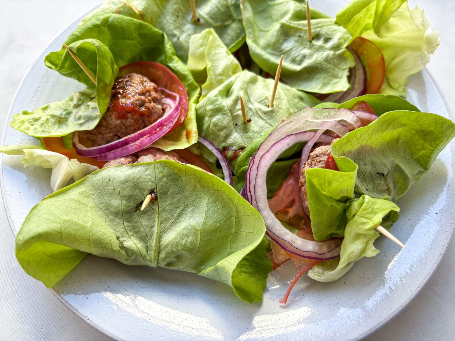 Finished bunless sliders on a plate in lettuce wraps.