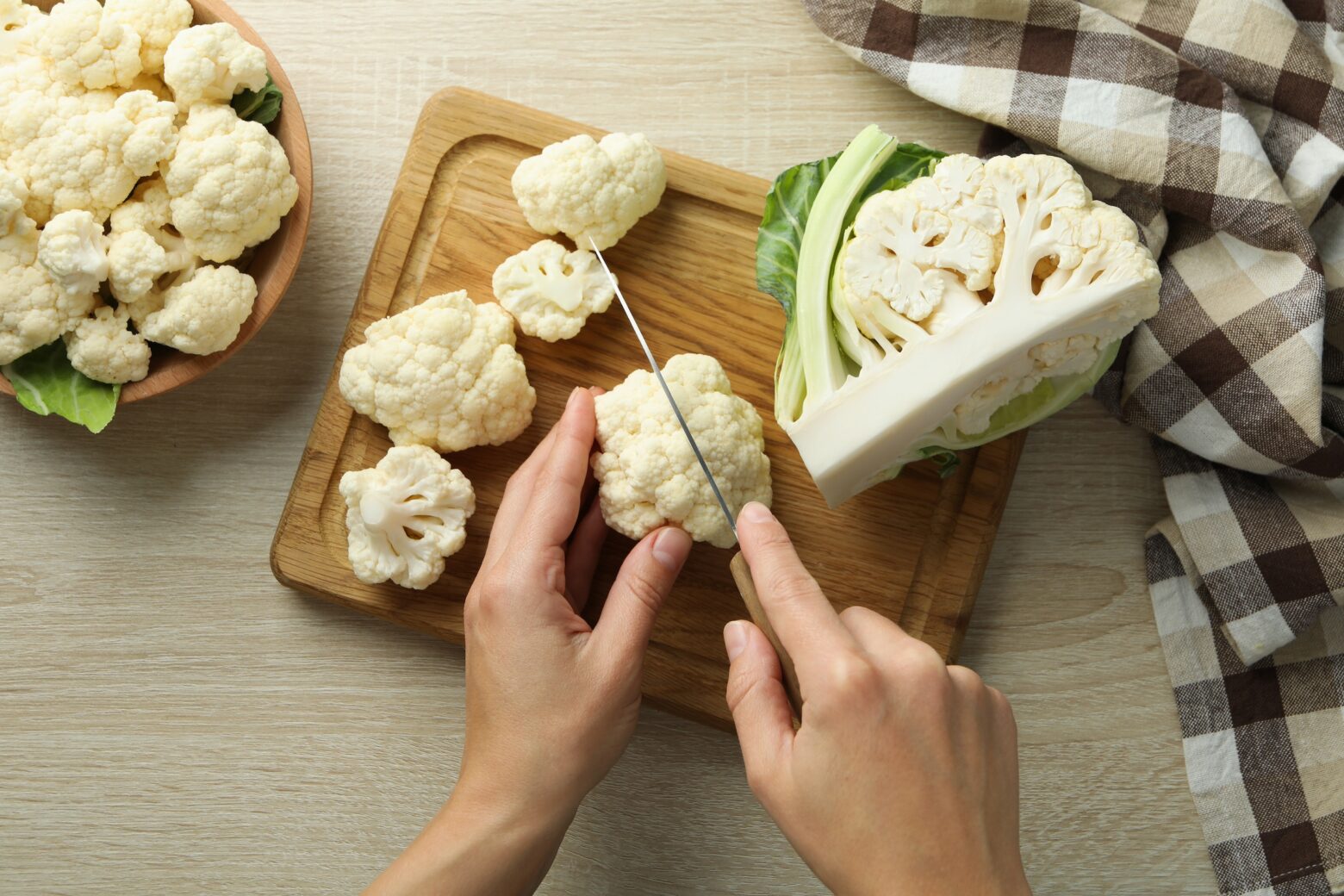 Learning cauliflower nutrition, cauliflower being cut on a cutting board.