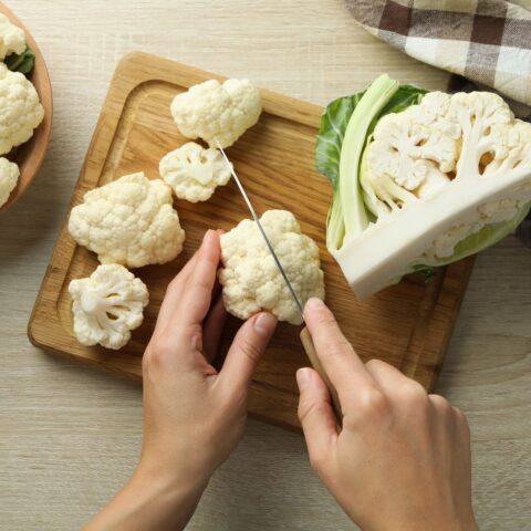 Learning cauliflower nutrition, cauliflower being cut on a cutting board.