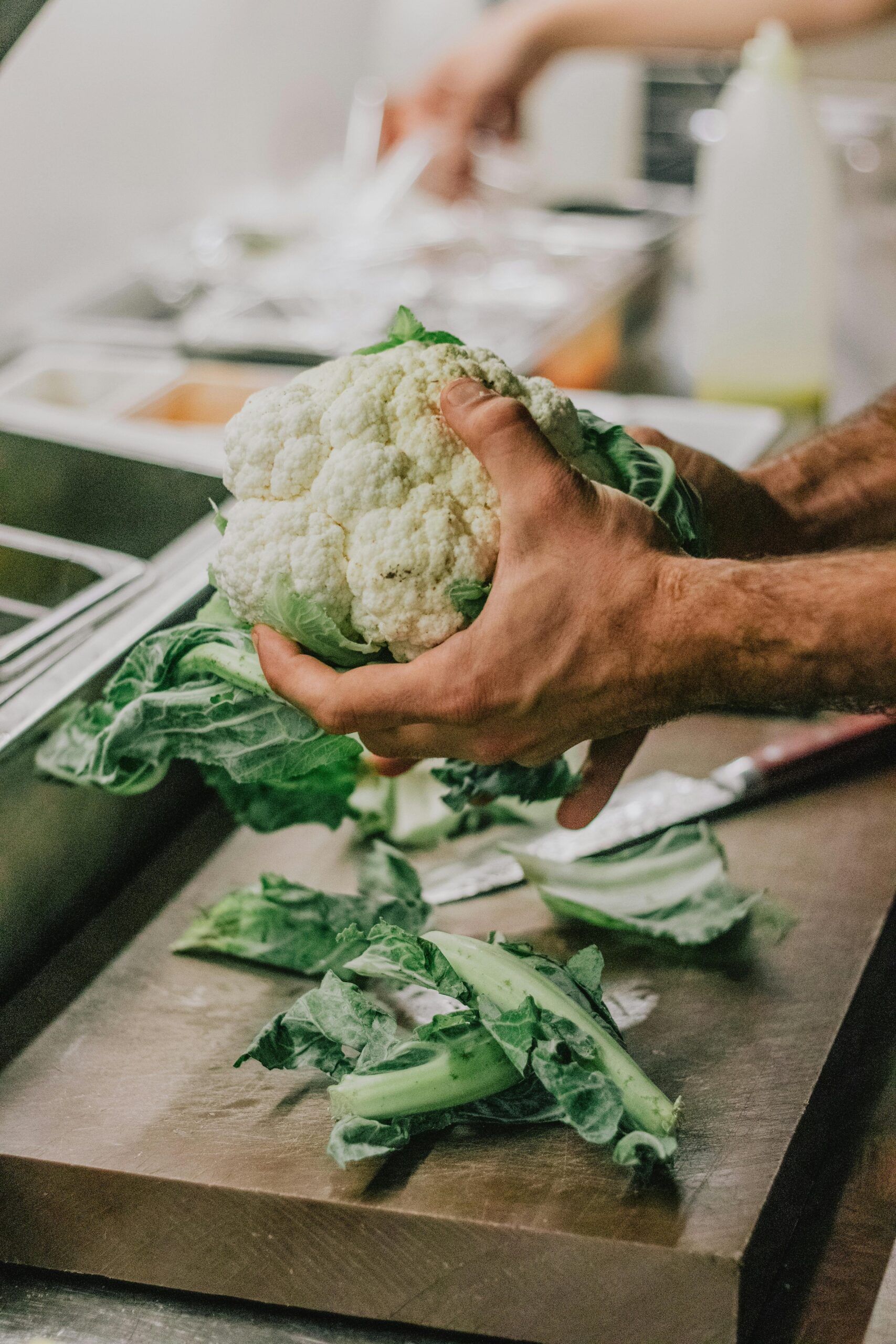 Cauliflower being prepped over a cutting board.