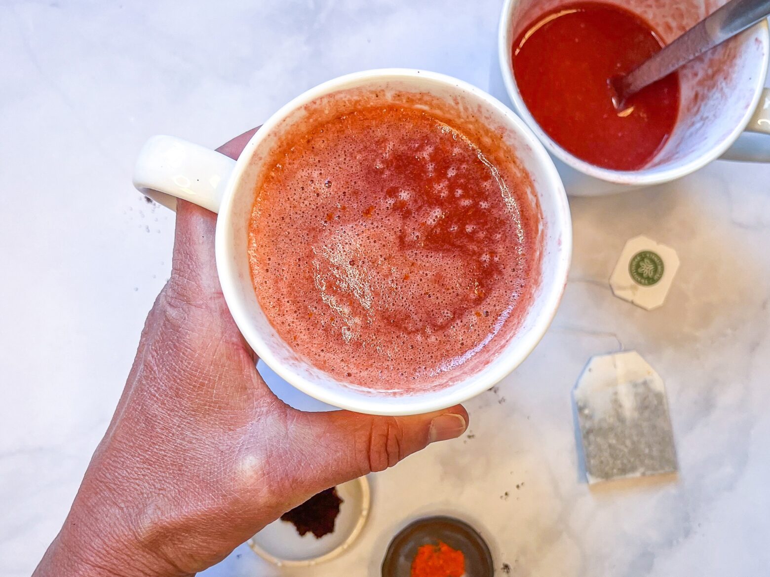 Elderberry citrus elixir being held in a mug.