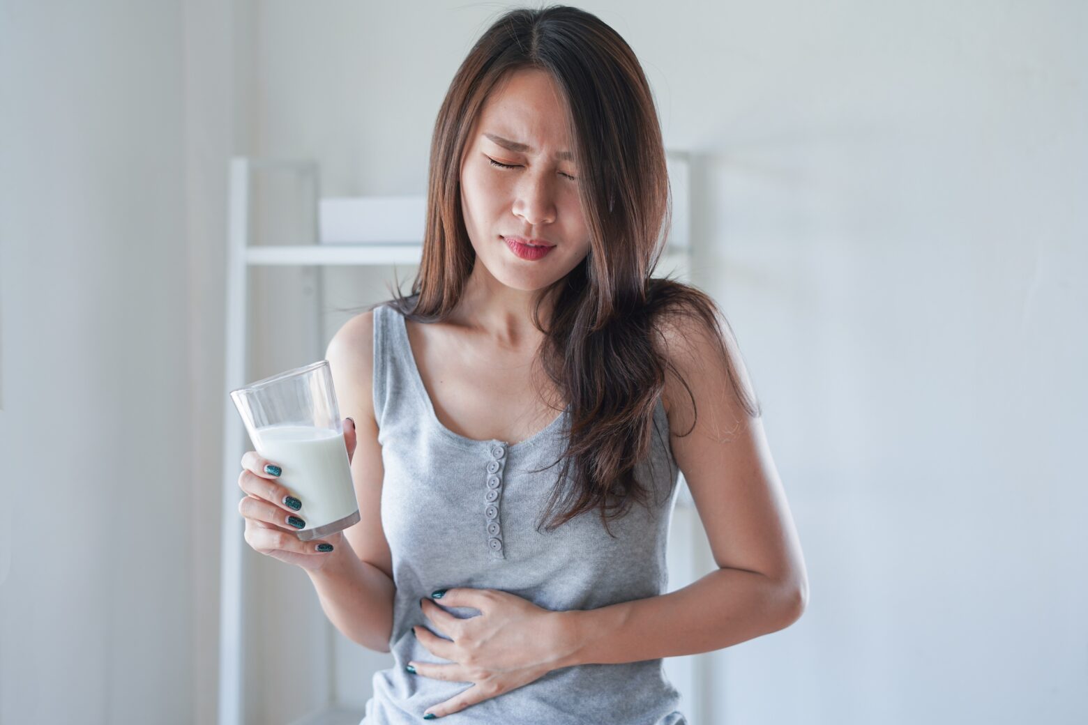 Women holding her stomach likley due to a food allergy or sensitivity.